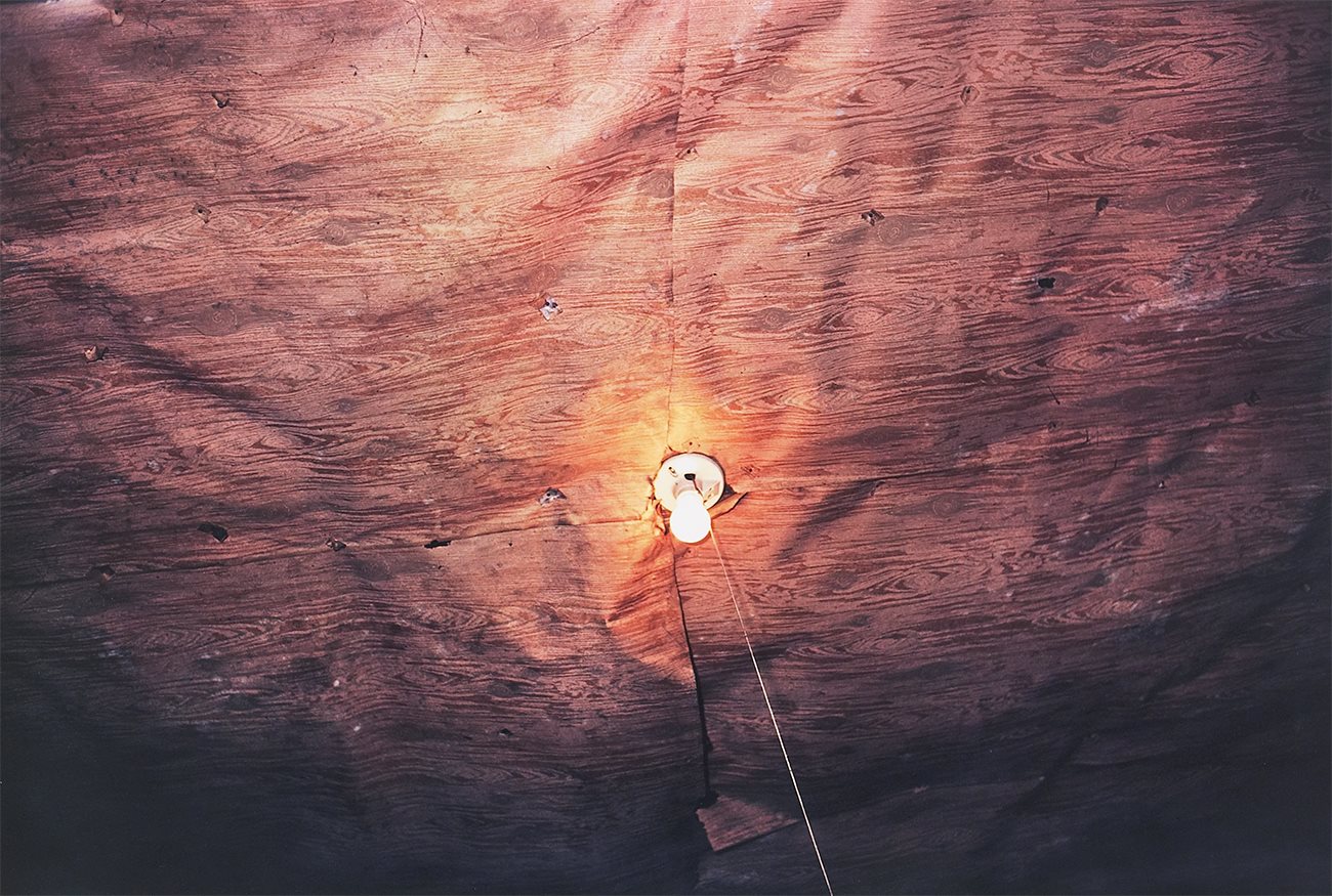 Dust Bells 2 – Light Bulb on Plywood Ceiling